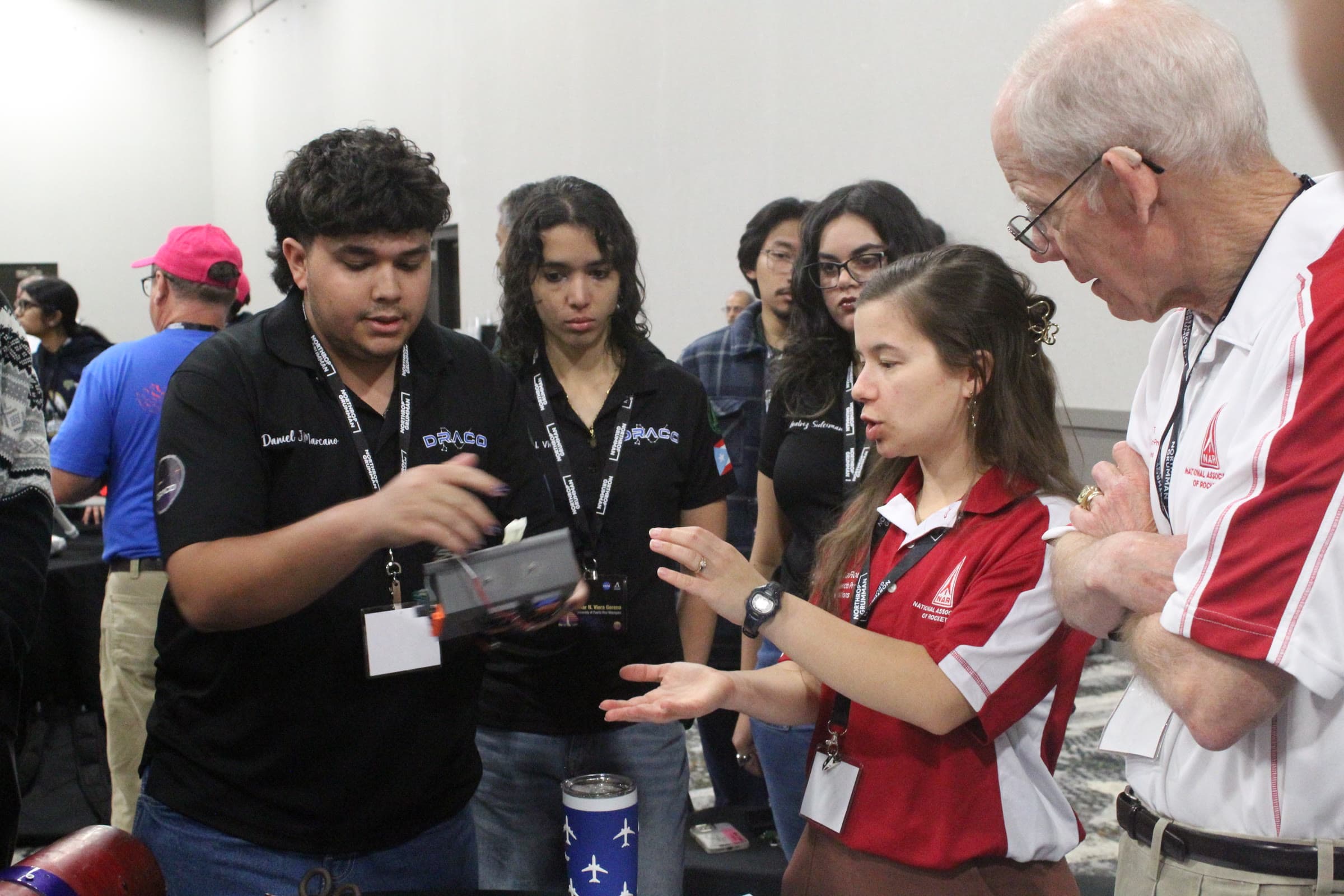 DRACO members presenting a rocket component to range officials during a pre-flight inspection at competition, with the team gathered around the table